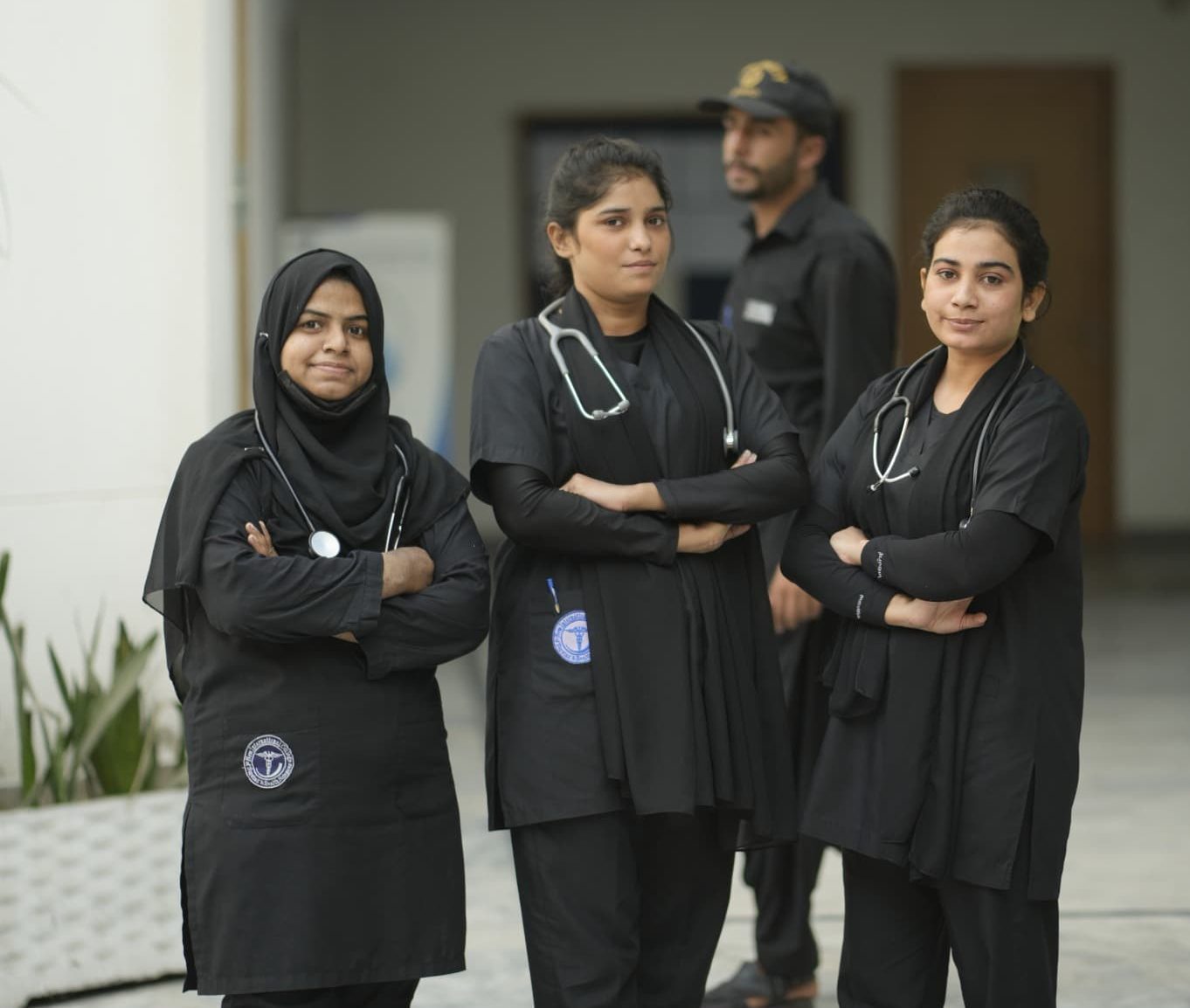 Nursing students in uniform standing outside New International College of Nursing & Health Sciences in Pakistan.